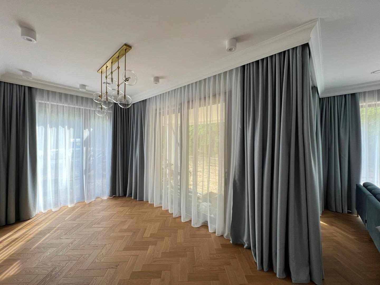 Szare zasłony i firany na całej szerokości przeszklonego salonu